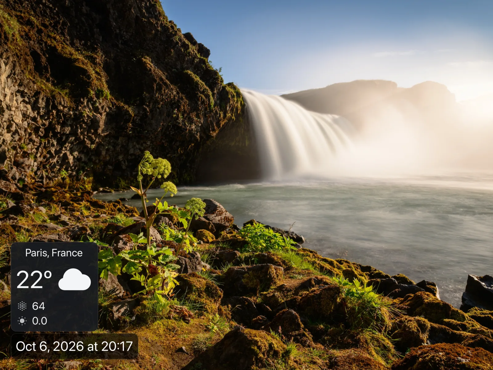 A digital photo frame showing a landscape photo with the weather and time