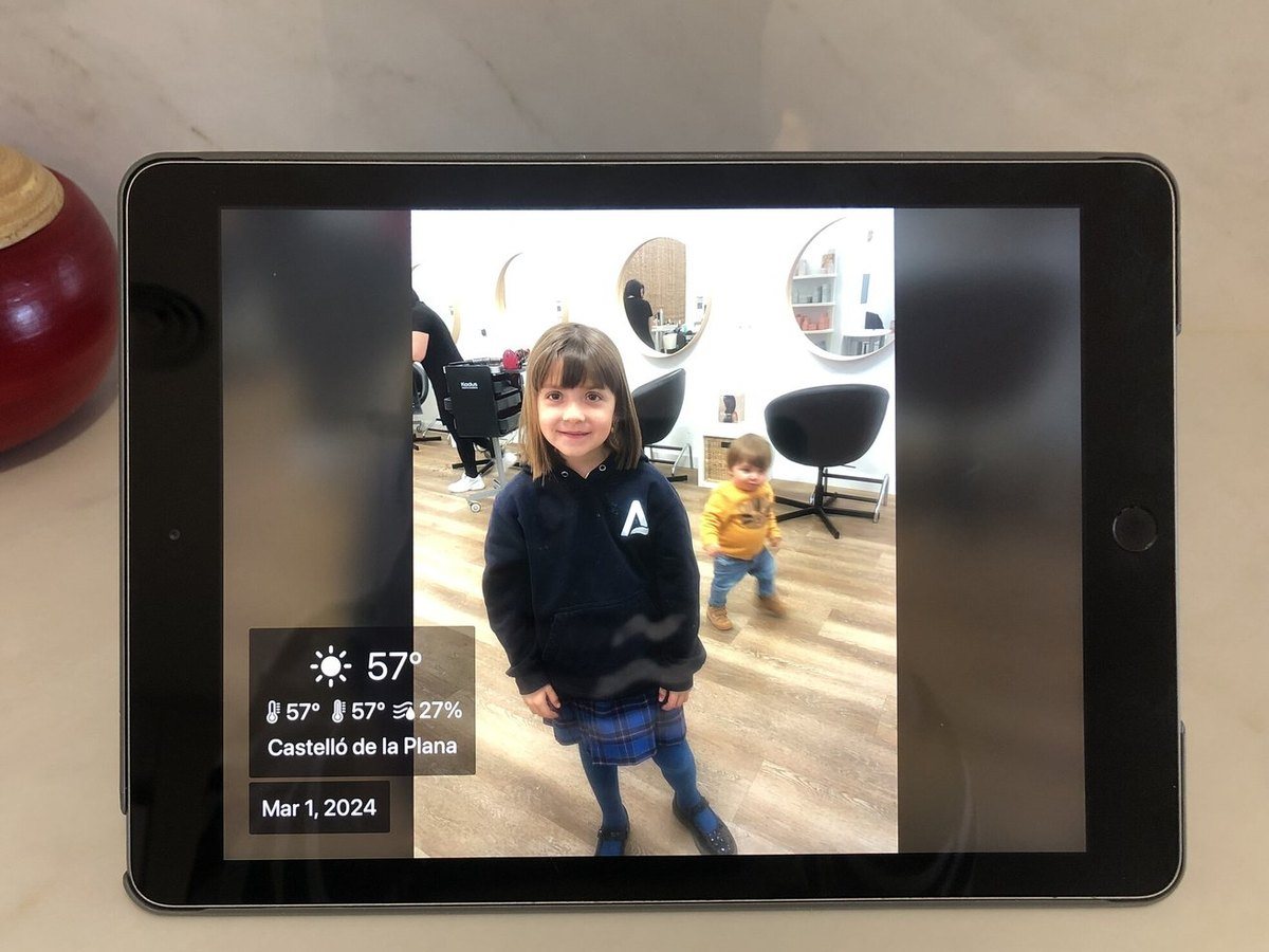 An old iPad used as a photo frame on a kitchen counter showing a child