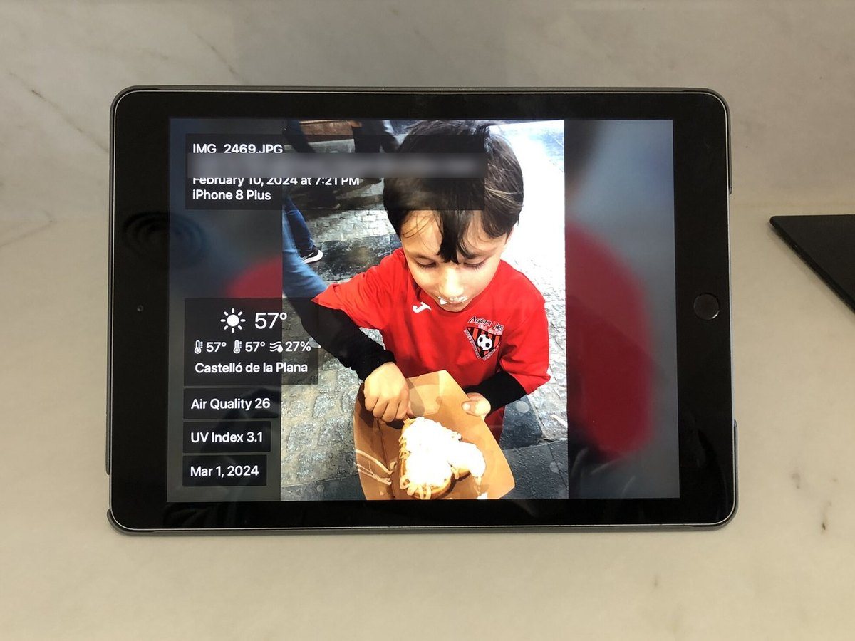An iPad photo frame on a kitchen counter showing a boy and the weather