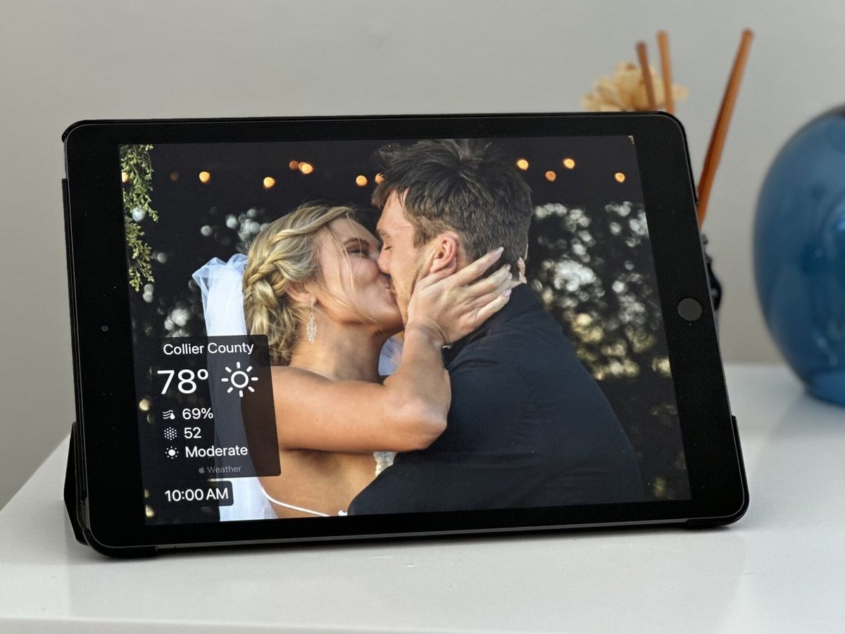 An iPad photo frame on a white dresser showing a couple