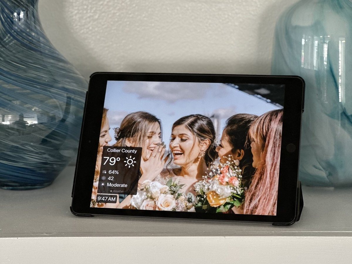 An iPad photo frame between two glass vases showing bridesmaids