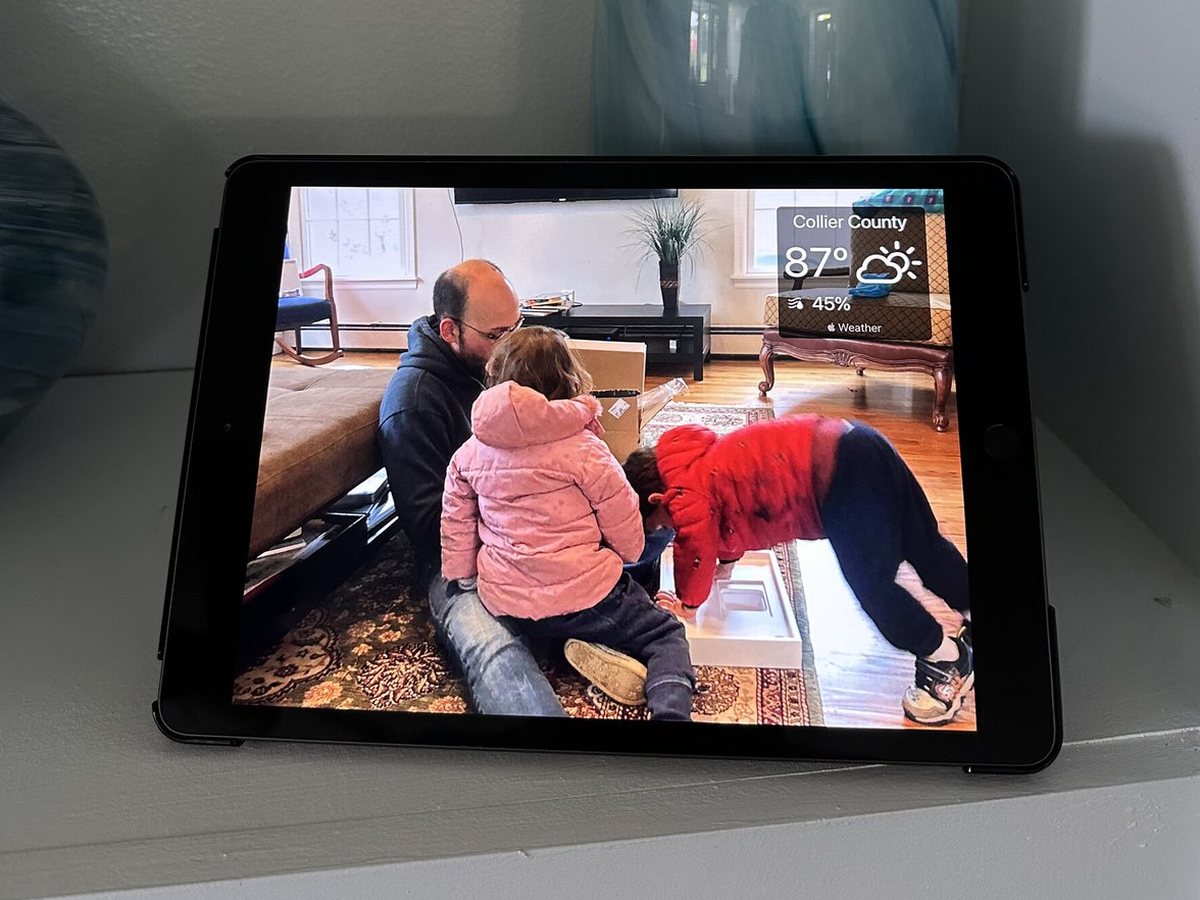 Grandparents playing with their grandchildren on an iPad photo frame on a shelf