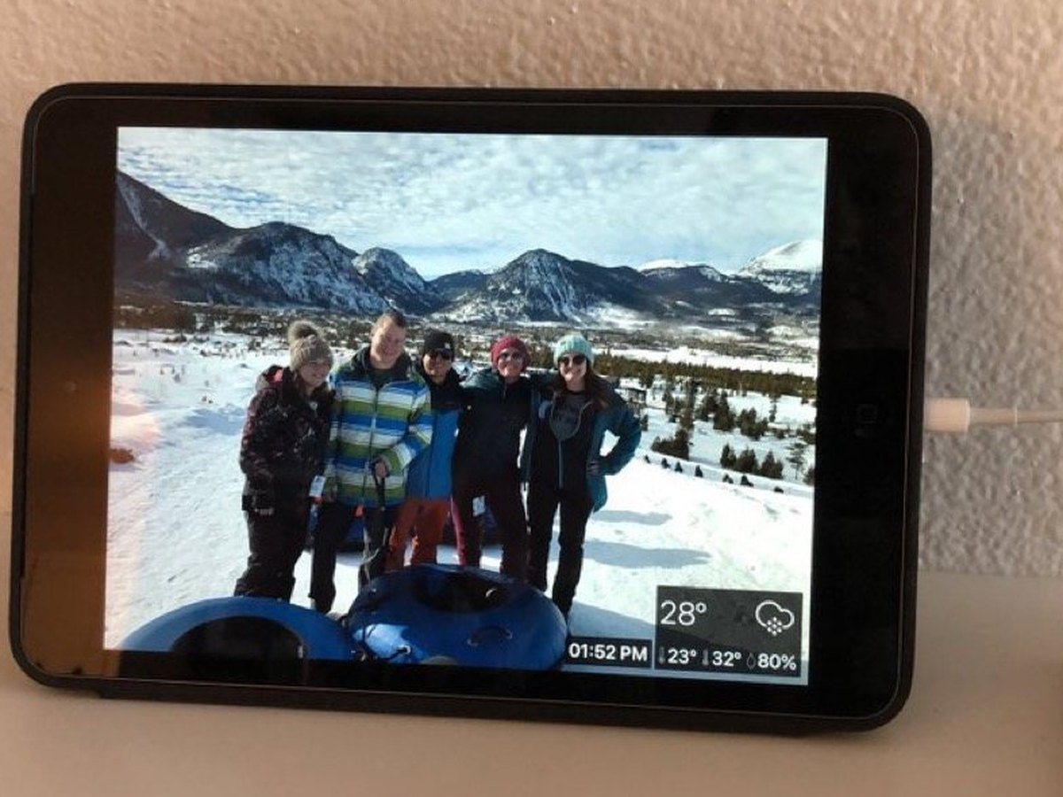An iPad photo frame on a kitchen counter showing a family in the snow