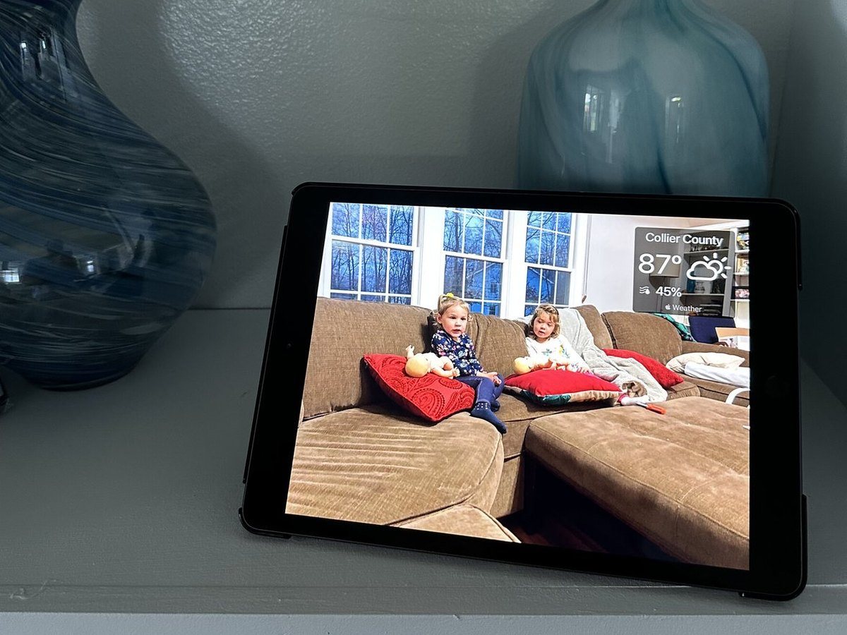 An iPad photo frame on a shelf showing children on a sofa